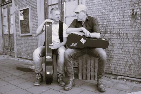 Schwarz-weiß Bild. Lothar Stadelmeier (links) mit Gitarre und Rik Schwarz (rechts) mit Ukulele